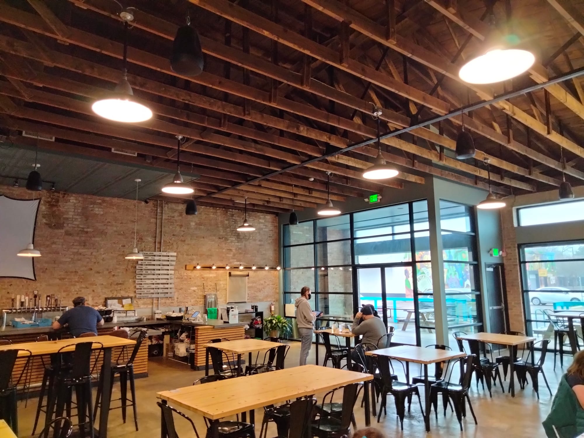Inside Revival Eastside Eatery, Waco, TX, with concrete floors, brick wall, and black chairs at dining tables