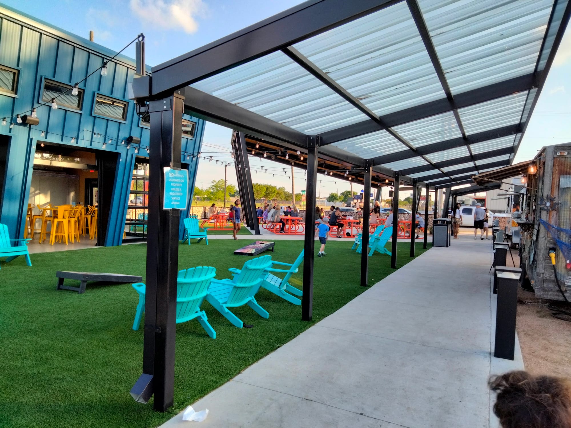 Route 77 Food Truck Park with covered walkway and cornhole, lawn chairs and bar area
