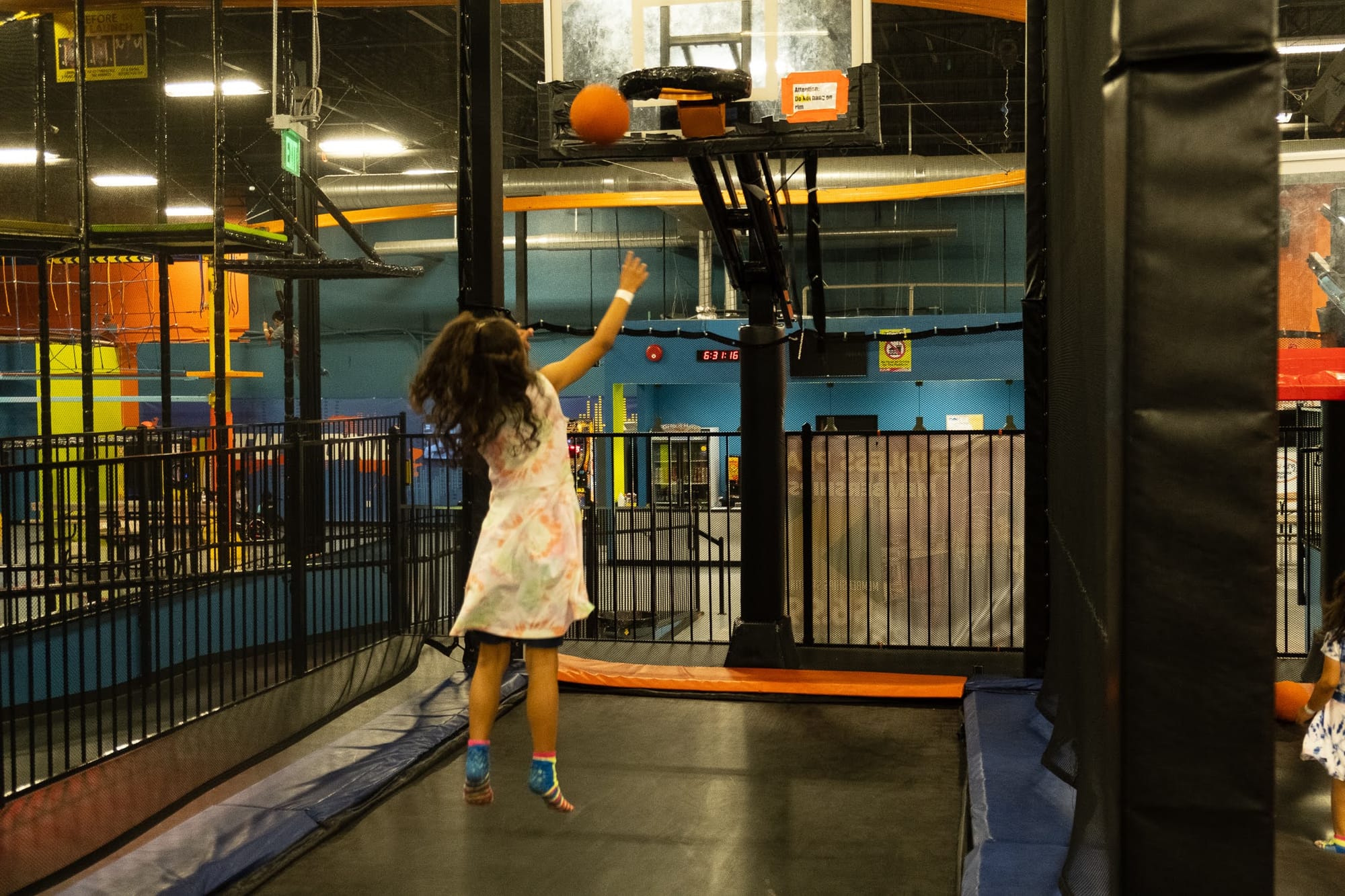 Girl throwing a basketball at Urban Air Waco indoor trampoline basketball court