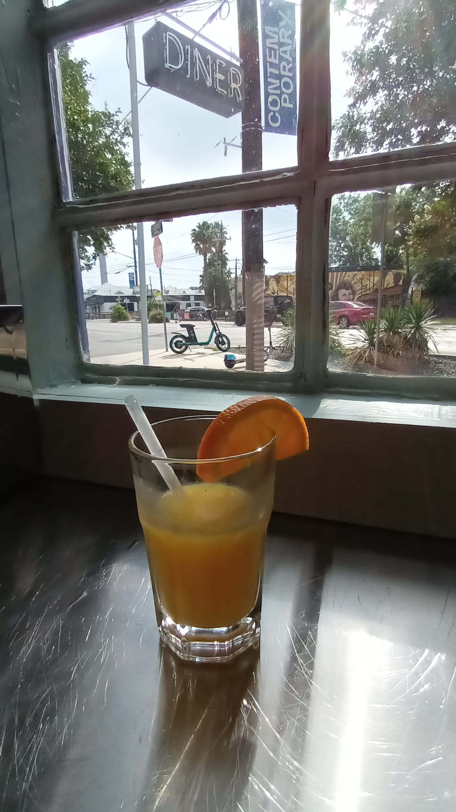 a glass of orange juice in front of a window at Beau's Tiny Diner in San Antonio, TX