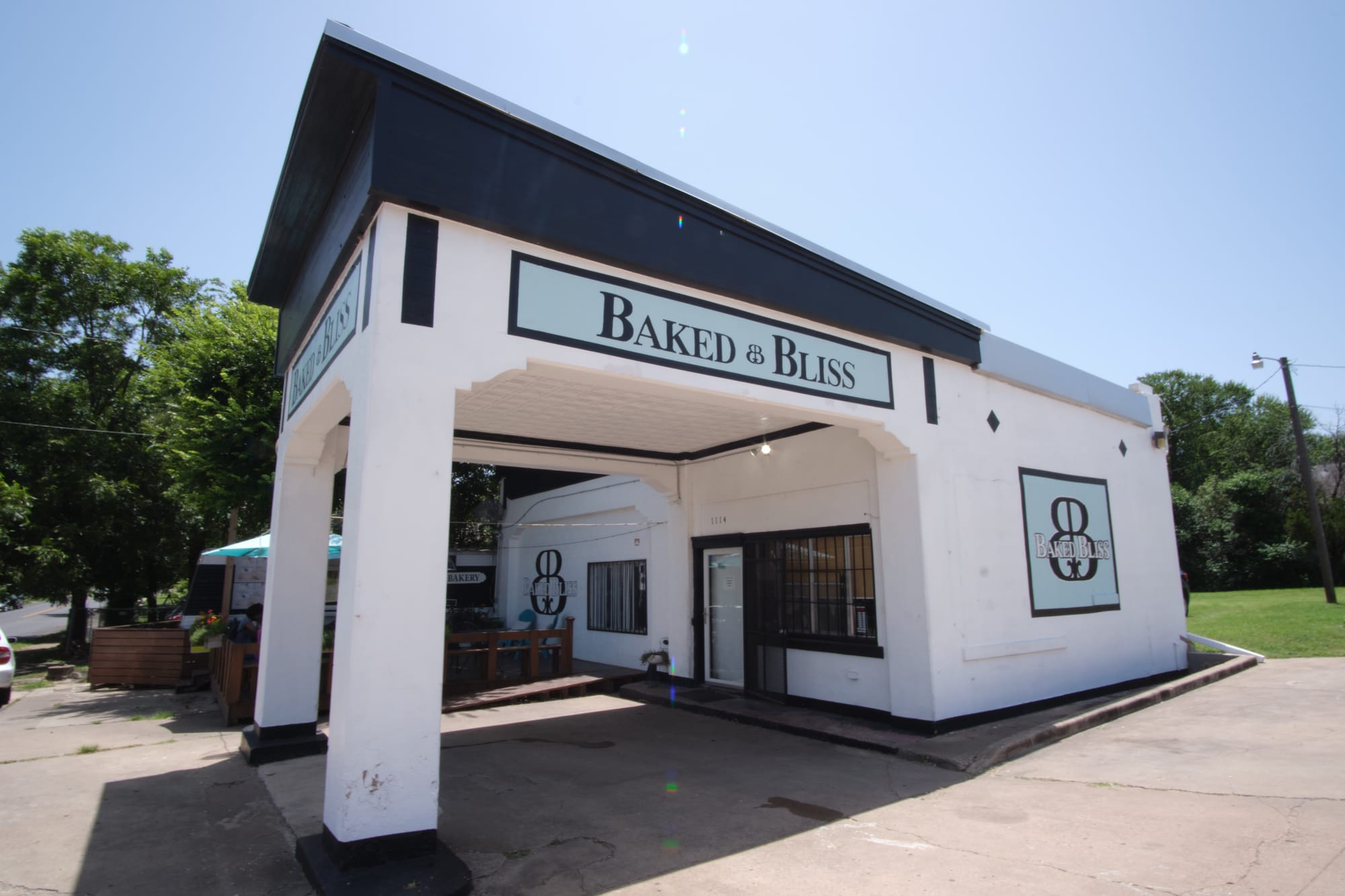 The Baked Bliss logo with patio chairs on the deck outside where you can sit down and enjoy desserts