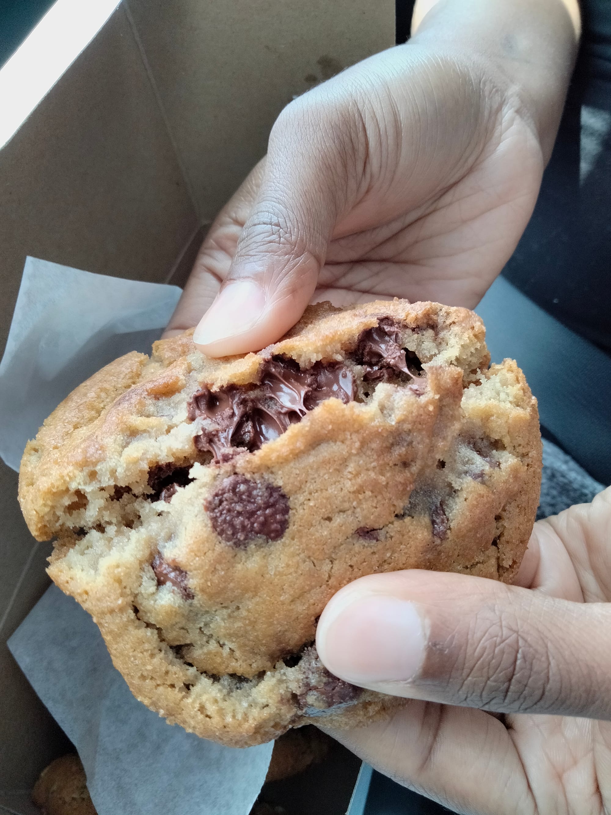 Momma Mo's Chocolate chip Cookie being broken in half with melted chocolate in the middle