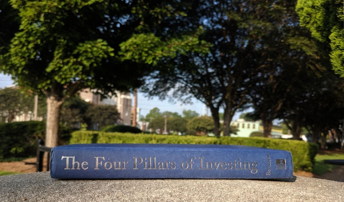 Side profile of The Four Pillars of Investing by William Bernstein on a concrete surface with trees in the background.