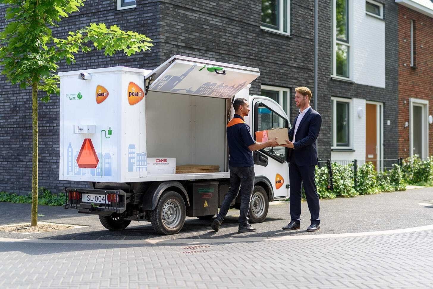PostNL delivery man hands parcel to customer, Postnl Wants to Switch to Delivering Mail Every Other Day