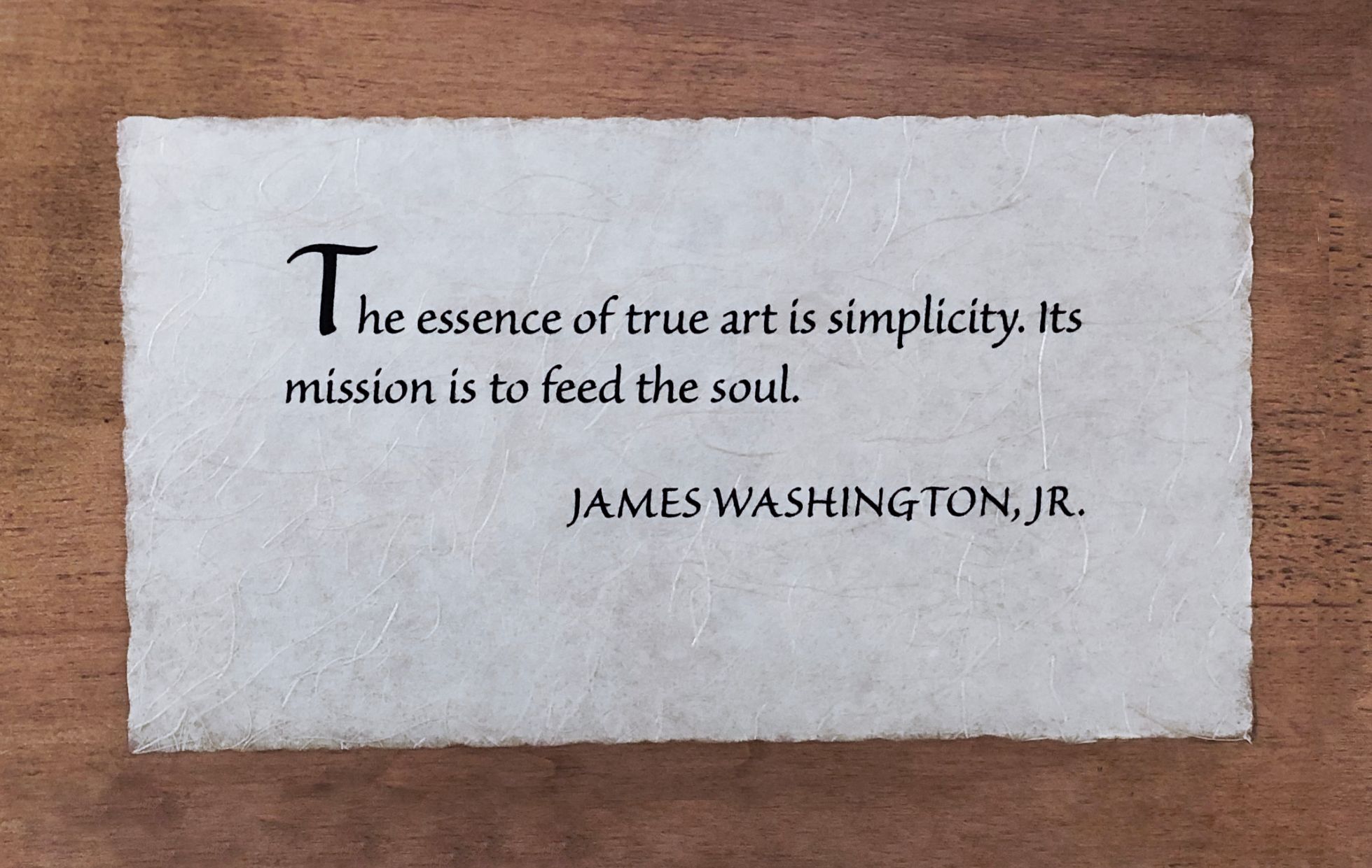 Photo of wooden plaque with James Washington Jr. quote: “The essence of true art is simplicity. Its mission is to feed the soul.”