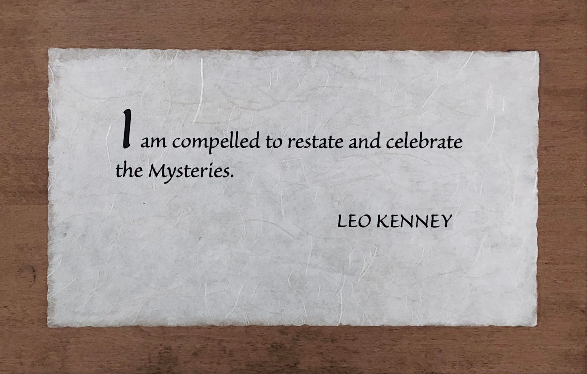 Photo of wooden plaque with Leo Kenney quote: “I am compelled to restate and celebrate the Mysteries.”