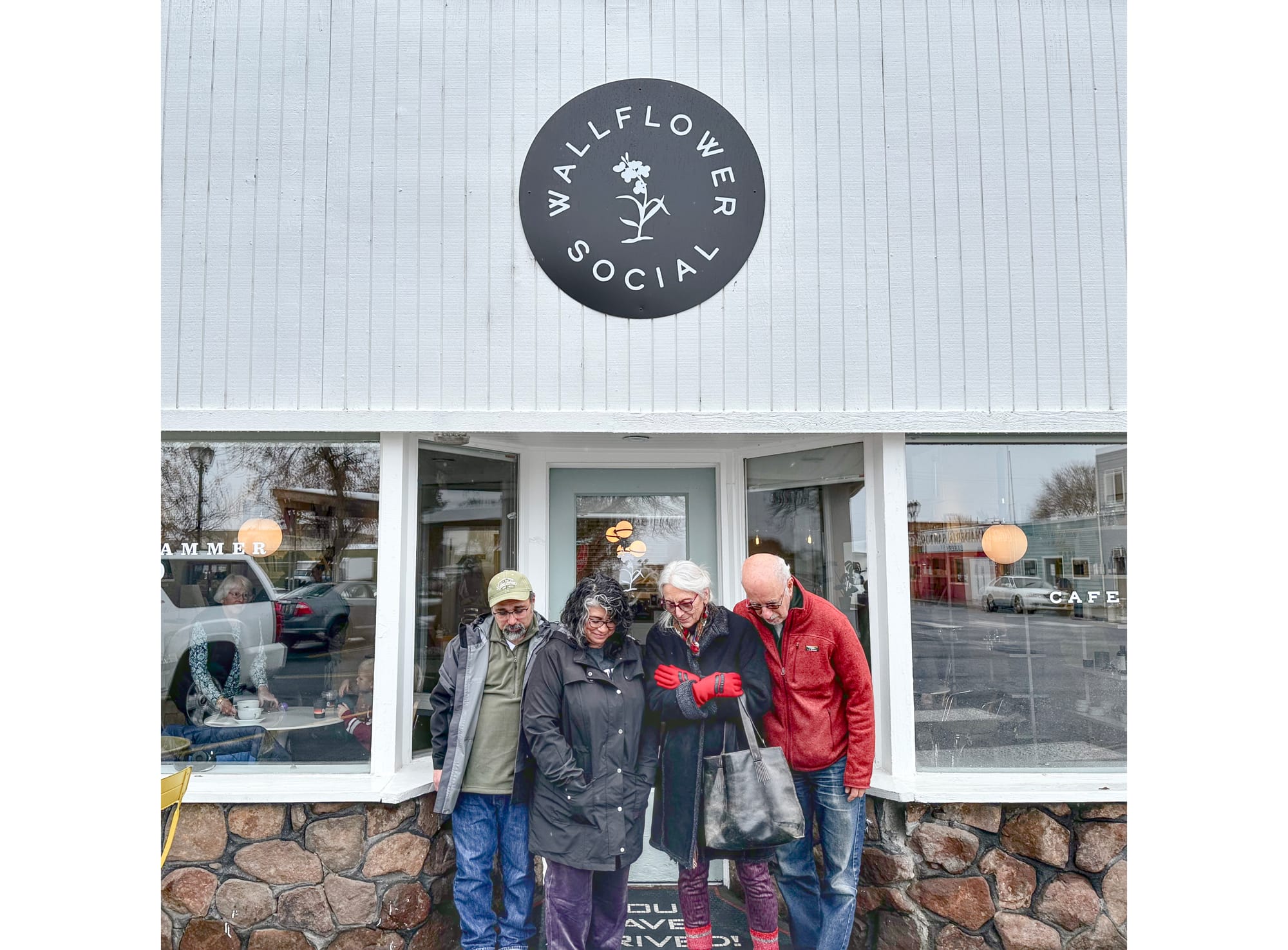 Two couples looking downcast standing outside a cafe