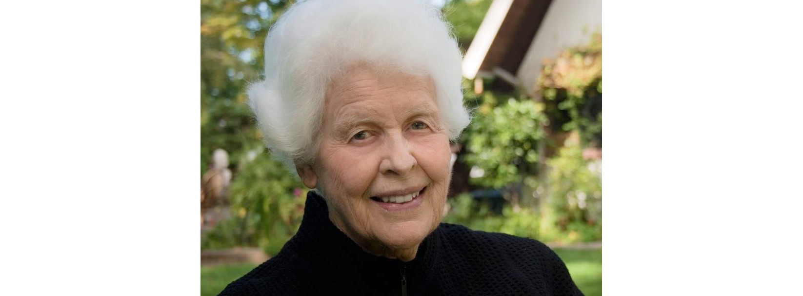Portrait photo of older woman with white hair and black sweater