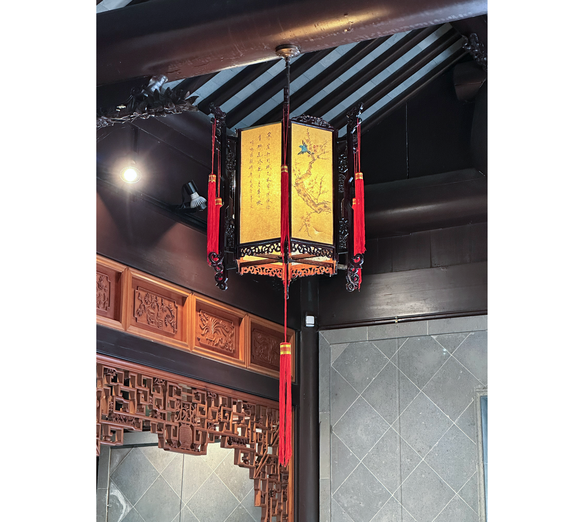 Photo of golden lantern with dark filigree and red tassel hanging from ceiling