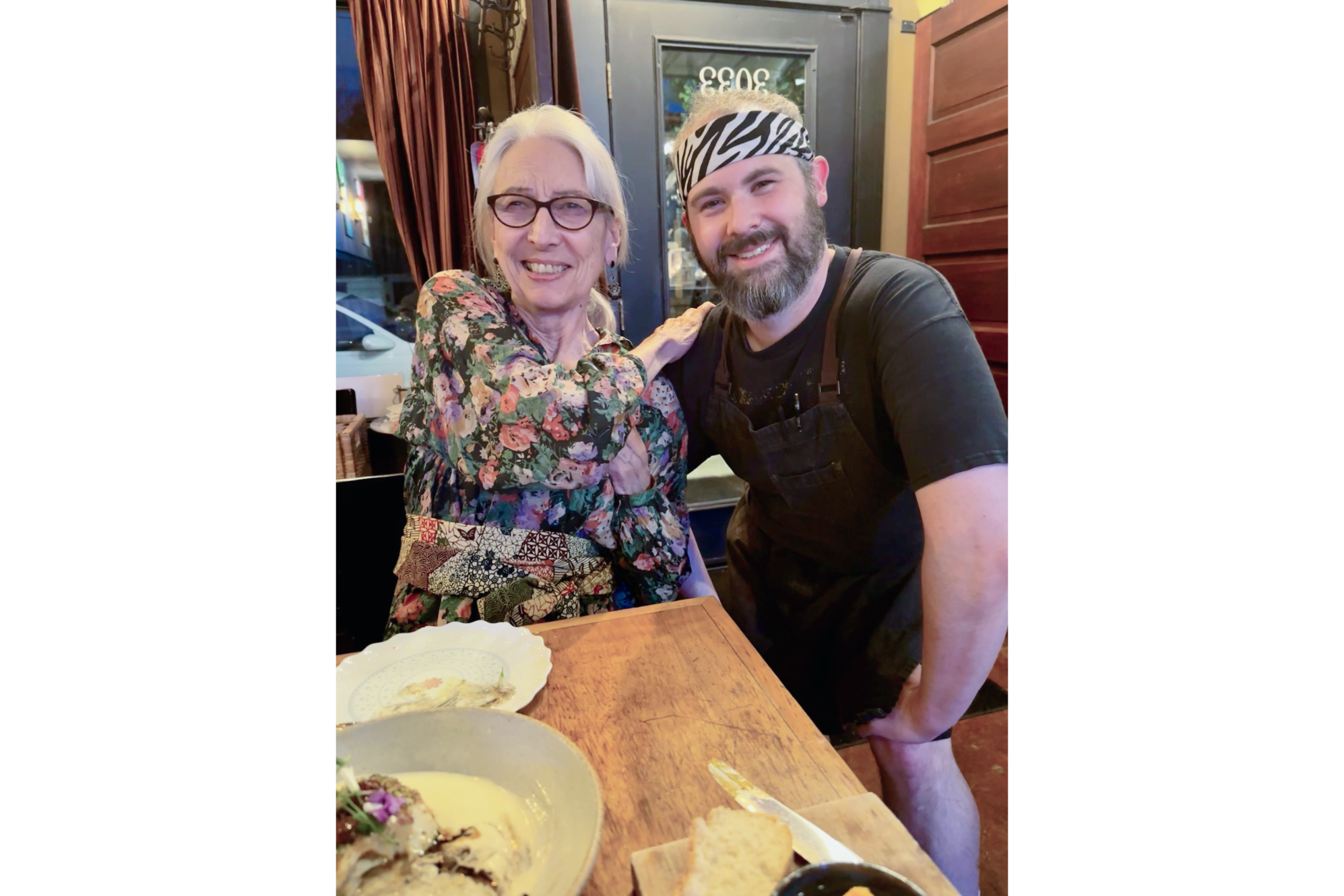 Photo of Sandra next to man wearing black and white bandana, both smiling at camera