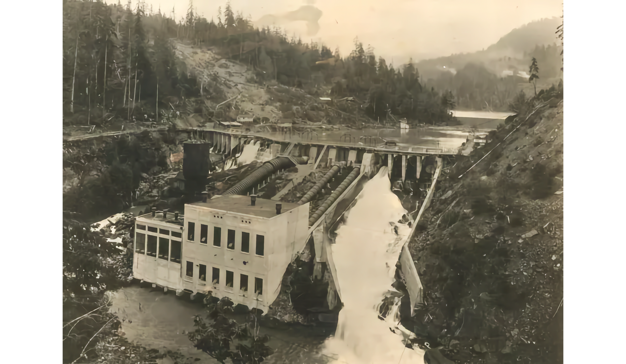 Archival photo in sepia for a dam with a building in front of it