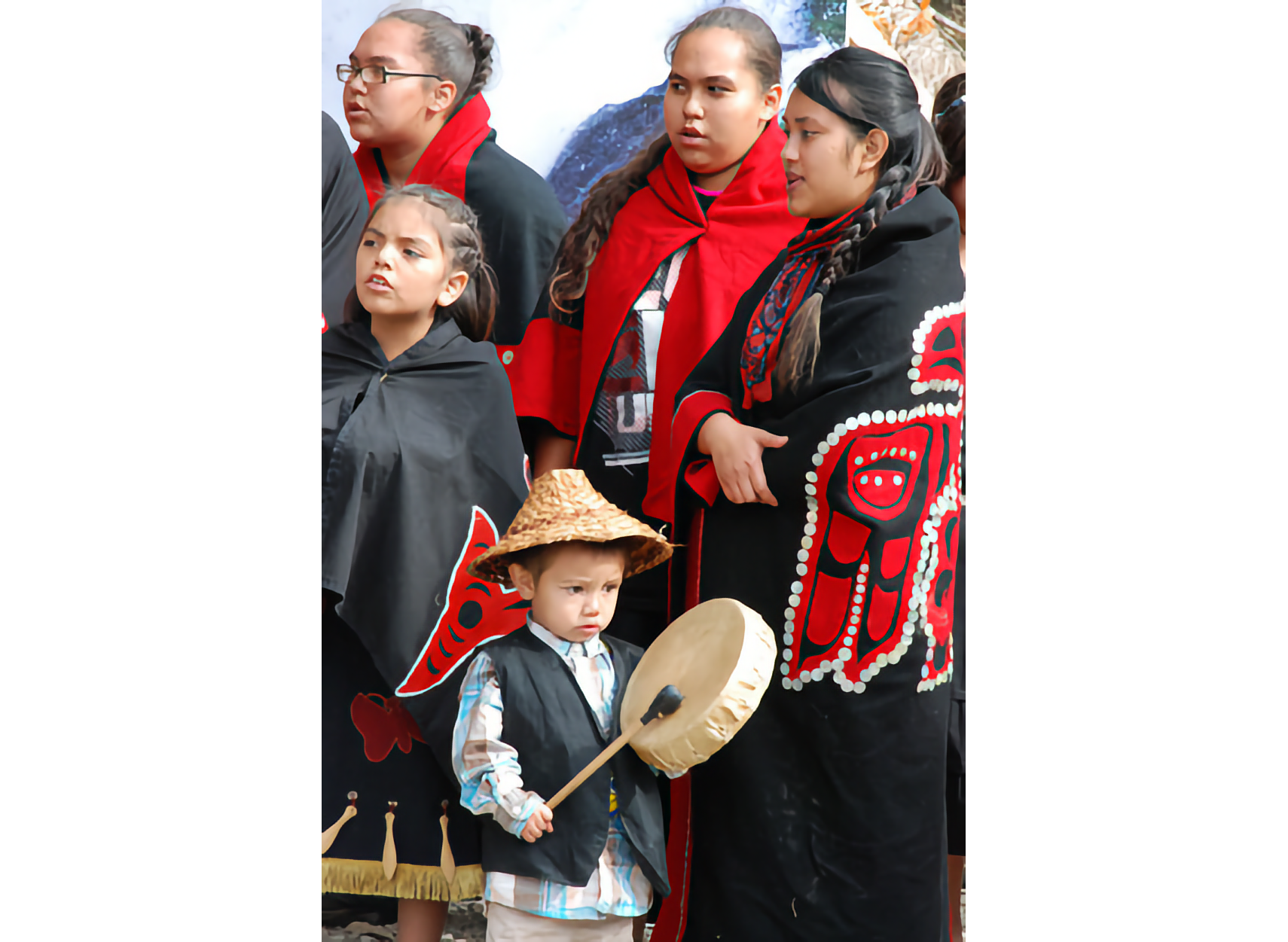 Photo of 4 women and a child in indigenous attire of black, red, and white