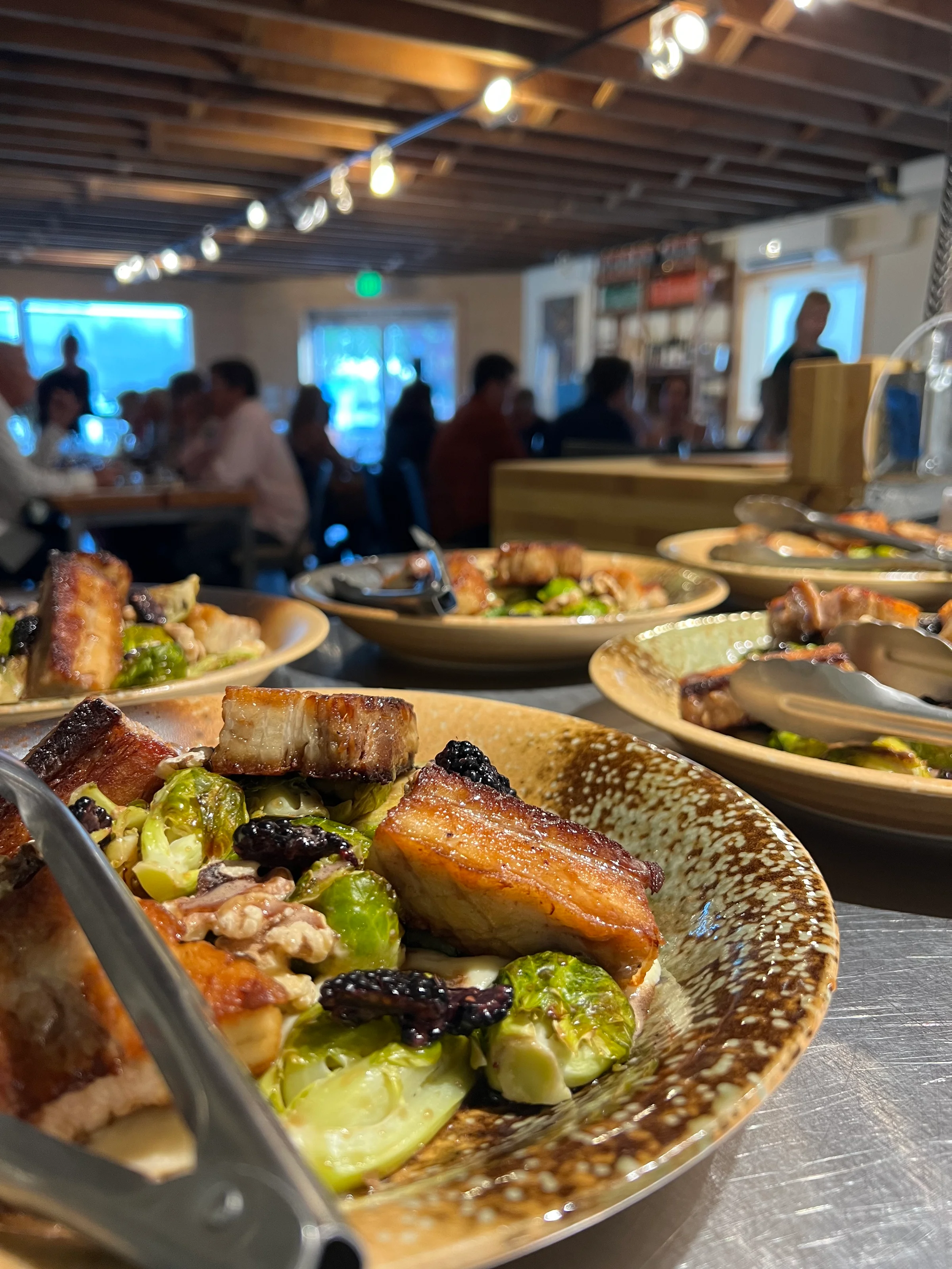 Closeup photo of plates of food, with diners in background.