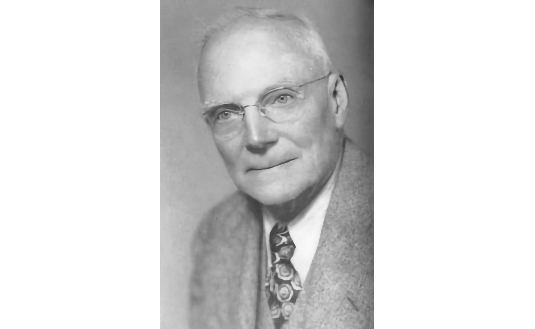 Black and white photo of a white elderly gentleman in wireframe glasses, short hair, , wearing a jacket, tie, and white shirt