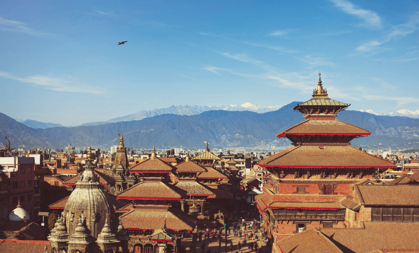 Photo of Asian temples in Kathmandu in foreground, with mountains in background