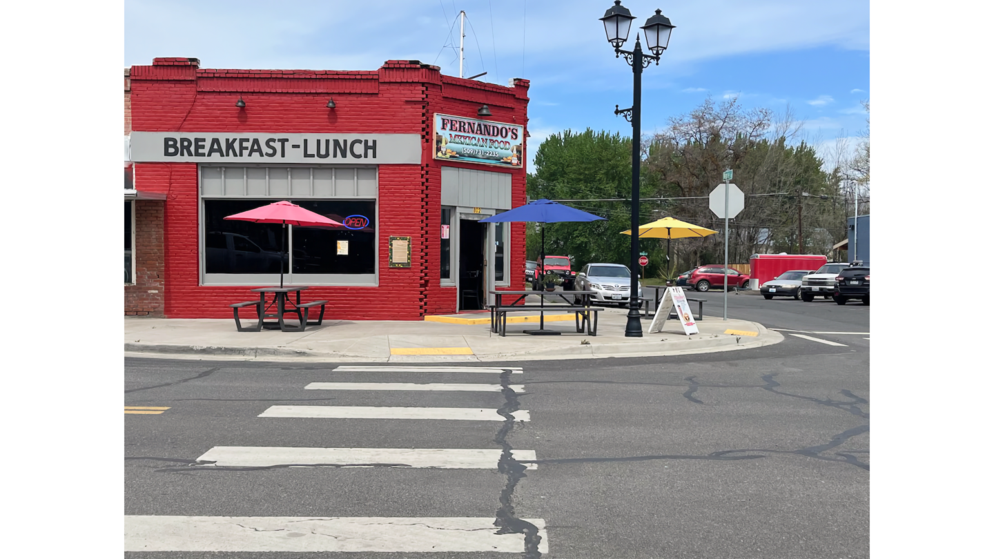 Fernando's Mexican Food, a red brick corner restaurant serving breakfast and lunch, with colorful patio umbrellas and outdoor picnic tables on the sidewalk.