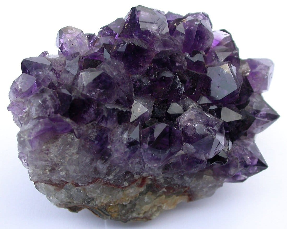 Natural amethyst druse showing deep purple quartz crystal points growing from grey rock matrix