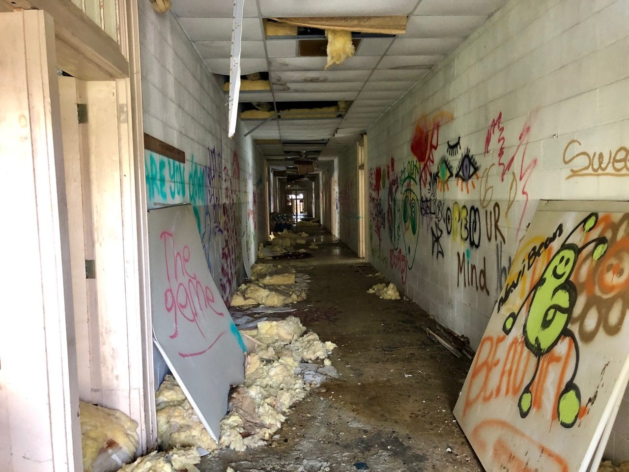 Empty fluorescent-lit elementary school hallway with closed doors, a classic liminal space