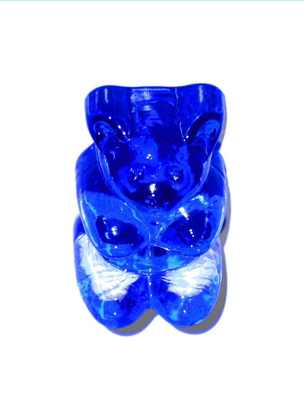 Single translucent blue gummy bear photographed against a white background