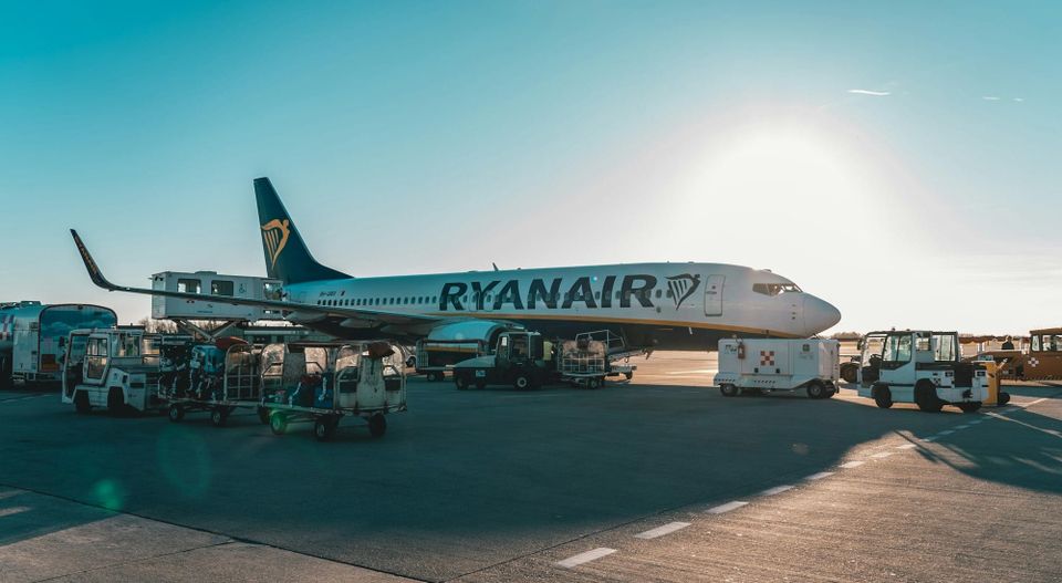 Photo of a commercial airplane parked at airport gate with jet bridge attached and blue sky