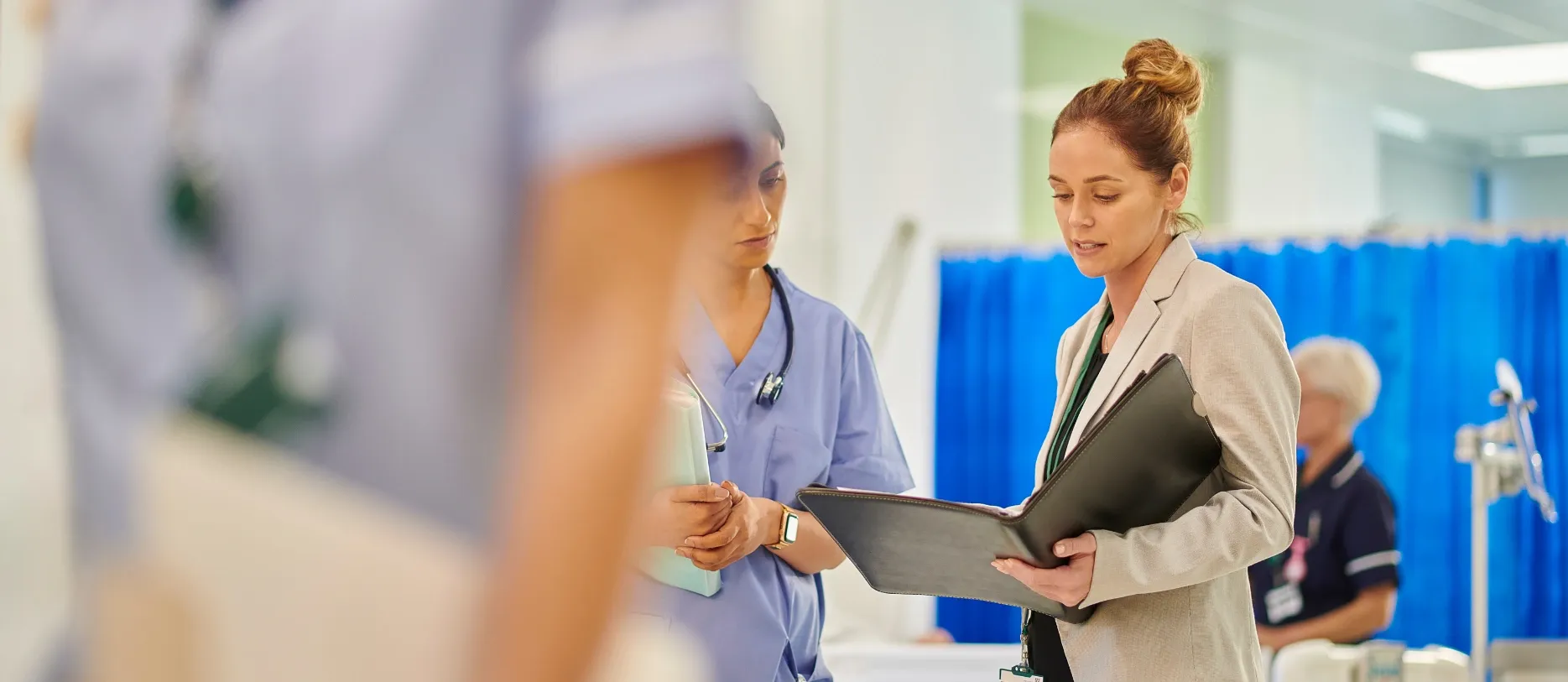 Stationsleitung bespricht Patientenakte mit Pflegekraft