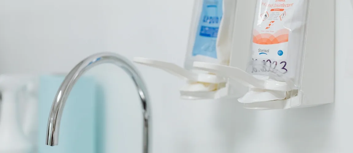 Nahaufnahme von zwei Desinfektionsspendern und einem Wasserhahn.