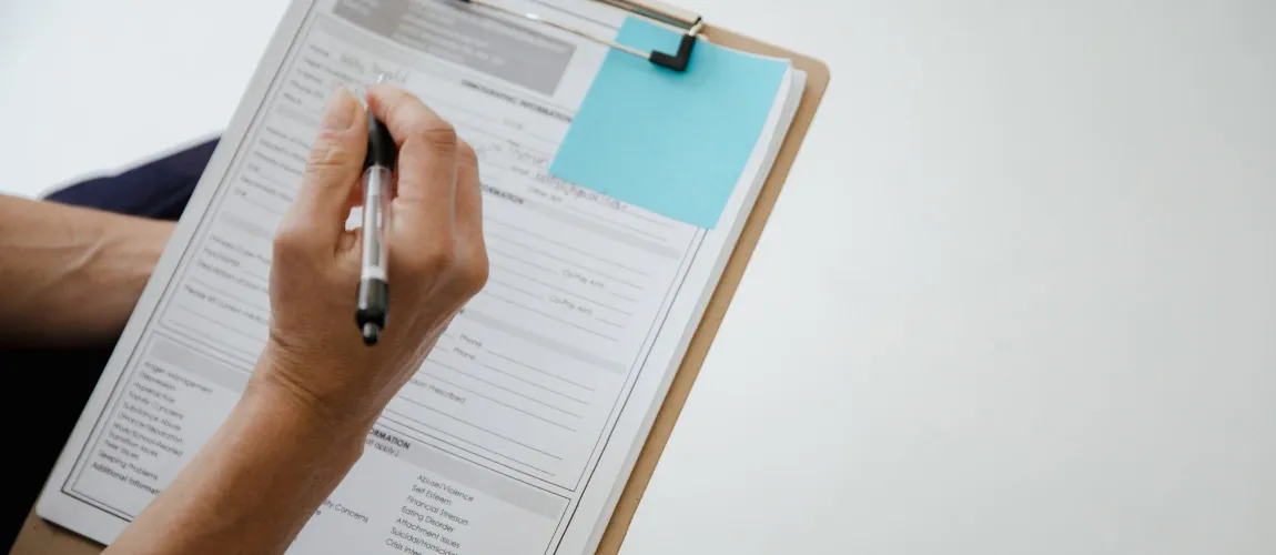 Eine Person hält ein Klemmbrett und einen Stift in den Händen.
