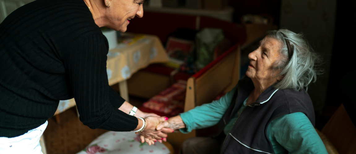 Pflegekraft gibt Patientin die Hand.