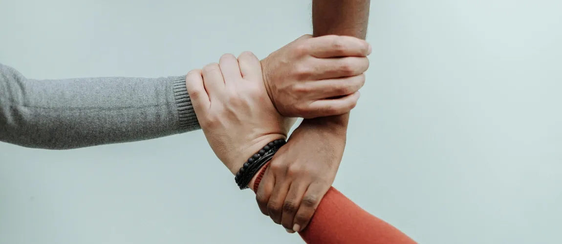 Drei Hände greifen ineinander.