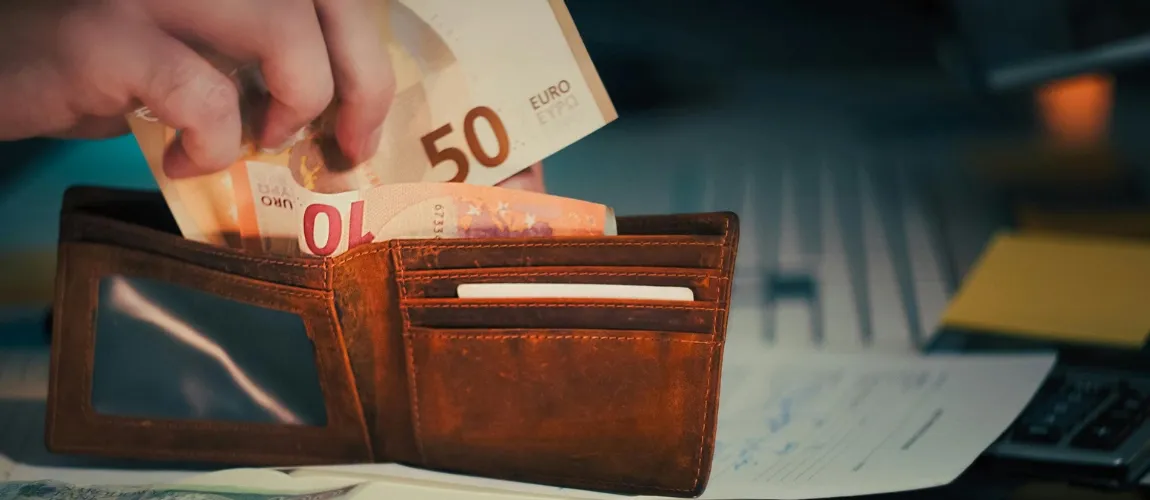 Eine Person steckt Euroscheine in einen Geldbeutel.