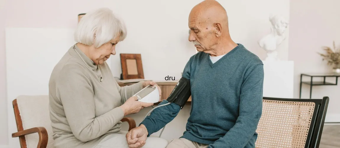 Eine Seniorin misst bei einem Senior den Blutdruck.