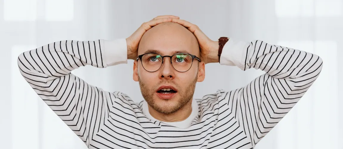 Ein Mann in einem gestreiften Oberteil mit Brille blickt stauend nach oben. 