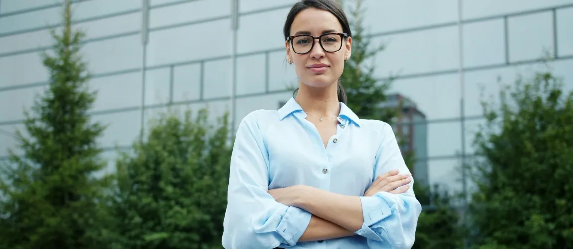 Eine Frau mit einer Brille und einer blauen Bluse schaut in die Kamera.