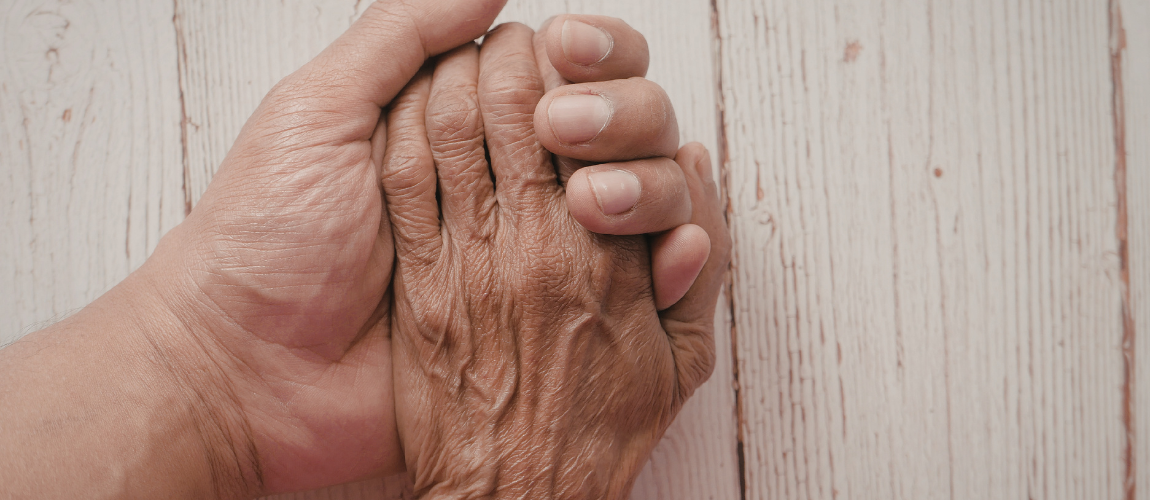 Eine jüngere Frau hält die Hand einer älteren Frau. 
