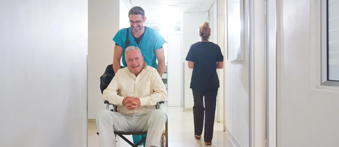 Ein Pfleger schiebt einen Patienten durch das Krankenhaus. 