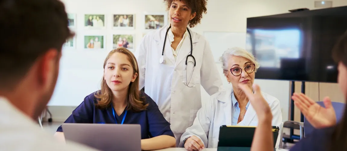 Es sind verschiedene Mitarbeitende eines Krankenhauses bei einer Besprechung zu sehen. 