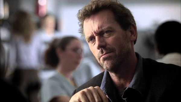 House wears a dark shirt and looks unimpressed.
