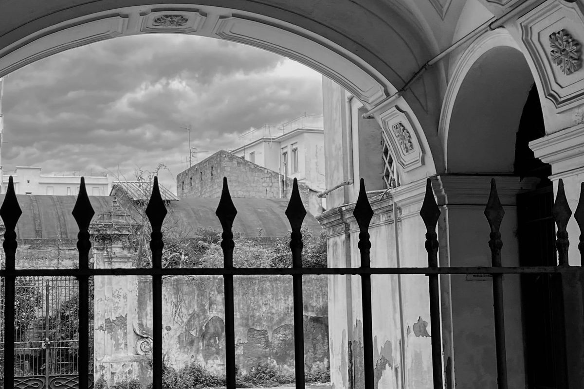 Arco e cancello in ferro su un cortile in rovina, in bianco e nero