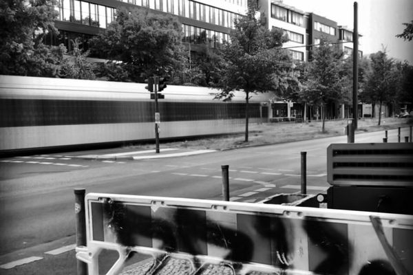 Tram in corsa, mosso, lungo una strada ferma, in bianco e nero