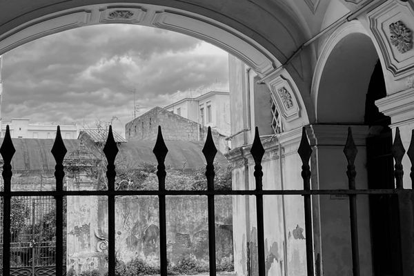 Arco e cancello in ferro su un cortile in rovina, in bianco e nero