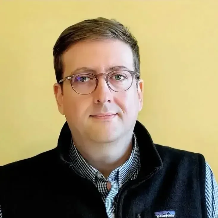 Retrato profesional de David Rhodus con camisa blanca y corbata oscura