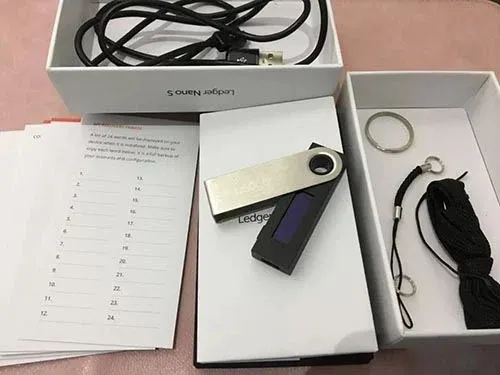 Tres tarjetas manuscritas con la frase de recuperación, llavero y correa del Ledger Nano S