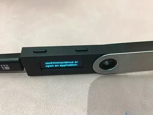 Pantalla lateral del Ledger Nano S mostrando ambos botones presionados simultáneamente