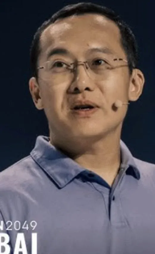 Xu Mingxing no palco, usando terno escuro, com o logotipo da OKX ao fundo