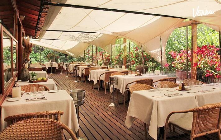 Restaurante elegante con terraza ajardinada perfecto para fiestas infantiles en la naturaleza urbana.