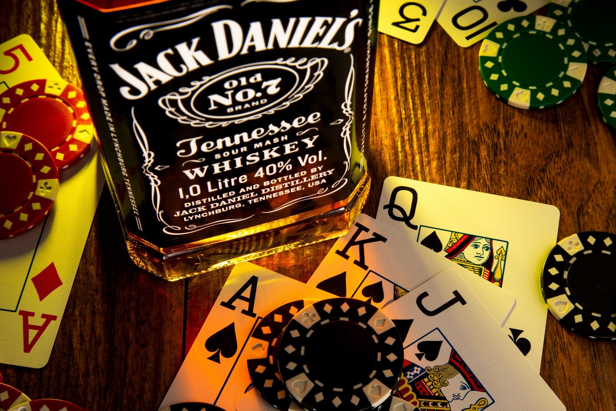 a bottle of jack daniels on a table with playing cards