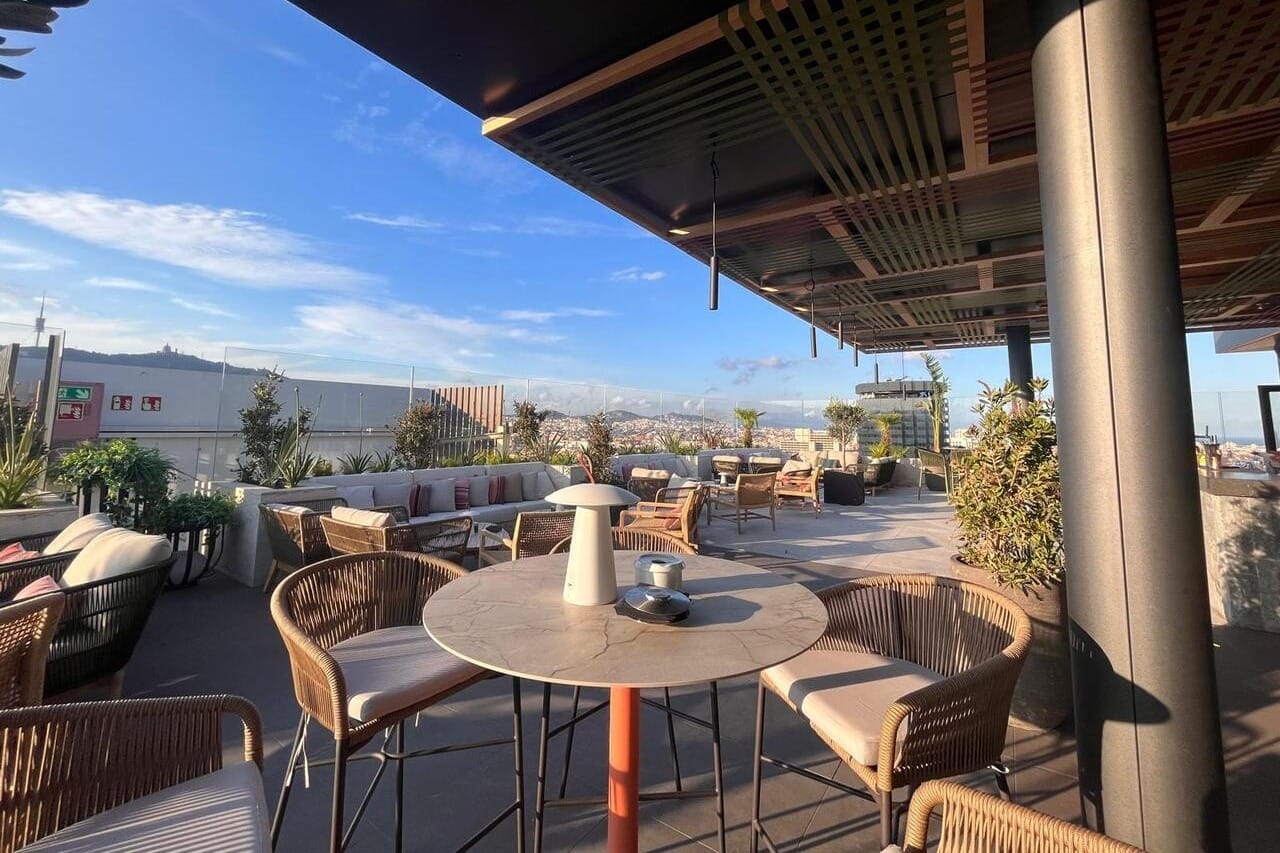 Rooftop elegante con vistas al skyline de Barcelona y ambiente sofisticado.