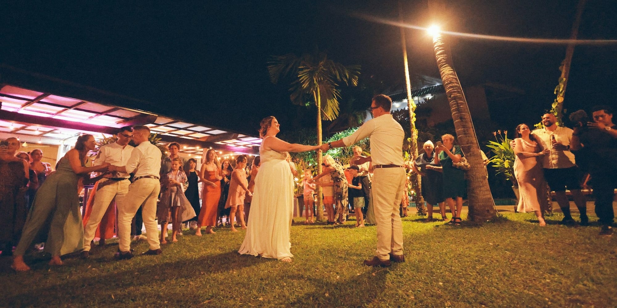 Bride and groom dance at outdoor wedding reception at night.