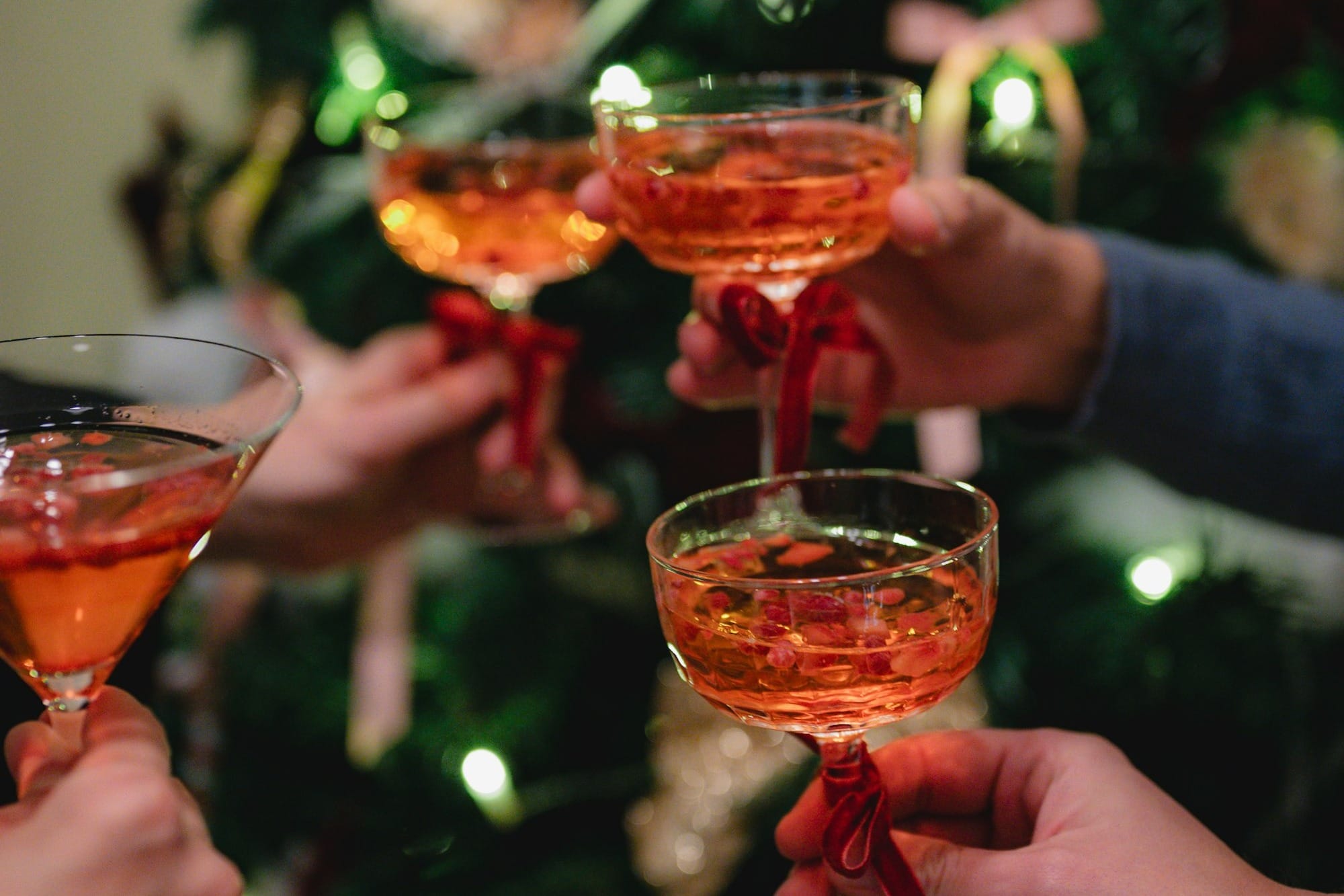 Hands clinking champagne glasses near christmas tree