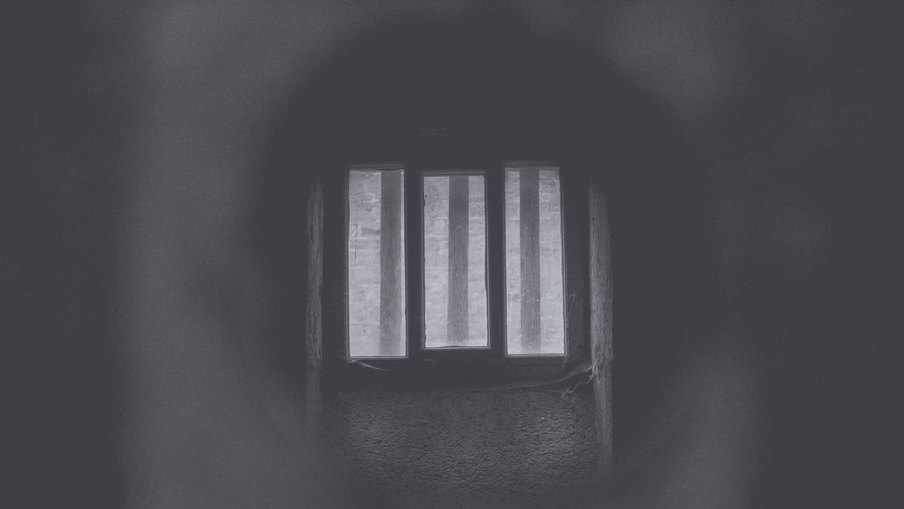 A dark tunnel with prison bars in sight.